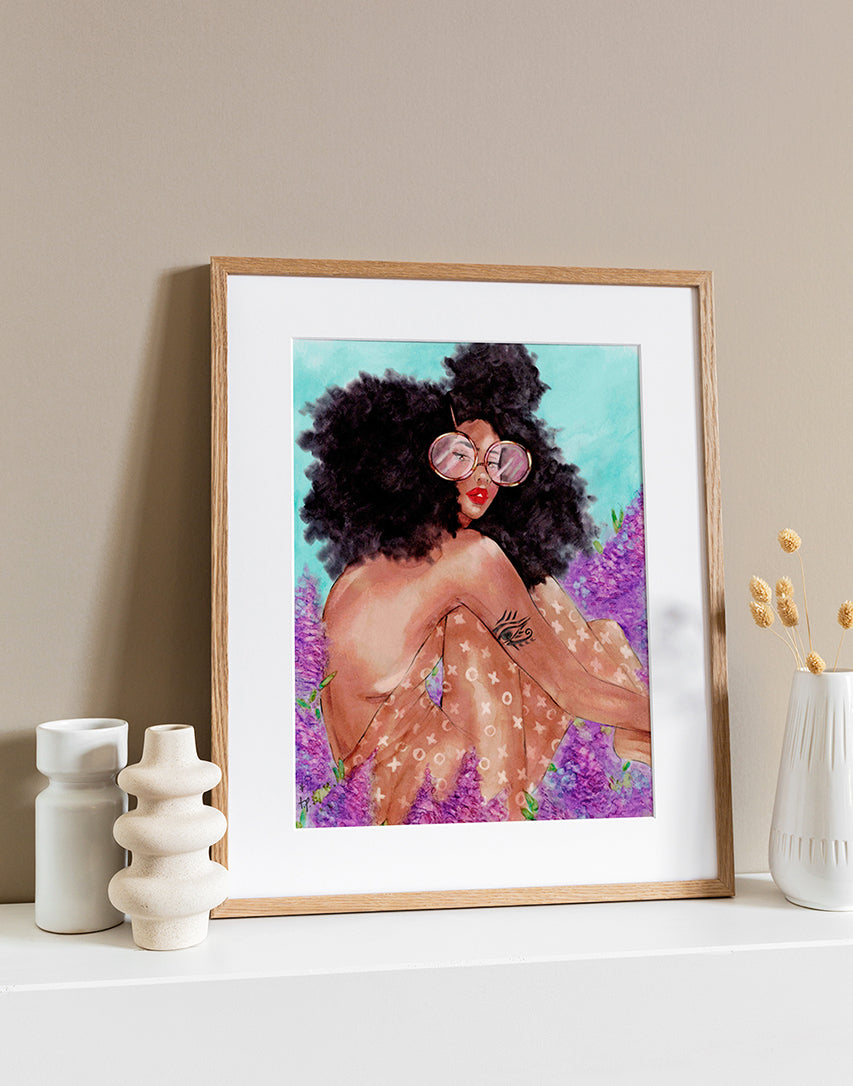 Illustration in a light frame of a black woman with big curly natural hair wearing an xoxo backless bodysuit and sitting among lilac flowers by Tatiana Poblah